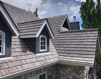 Close up of a residential roof with light blue-purple shake tiles