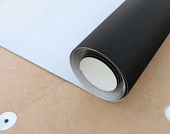 Close up of a rolled up single-ply roofing sheet being unrolled