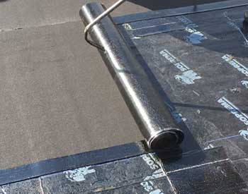 Close up of a Soprema membrane being unrolled on a commercial roof by a worker out of the frame