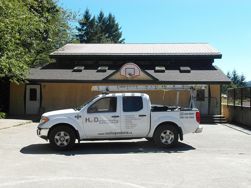 Side view of a High Definition Roofing white pickup in front of a home they recently worked on